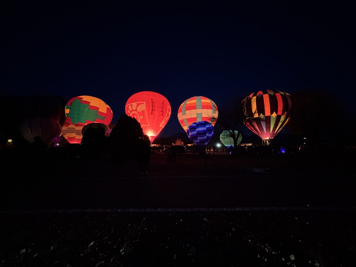 Balloons lit from within at dusk during a balloon glow in Albuquerque