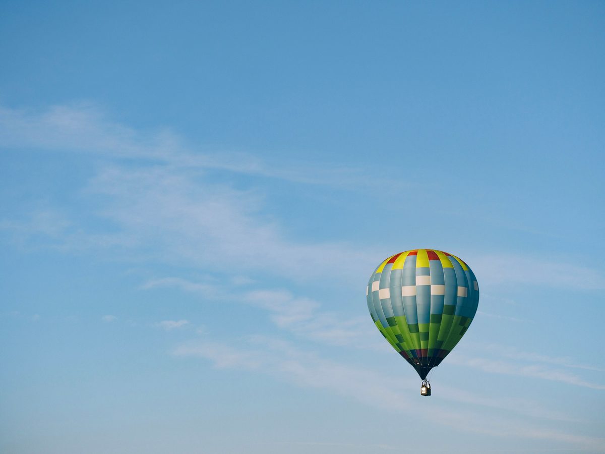 A hot air balloon climbing through open blue sky