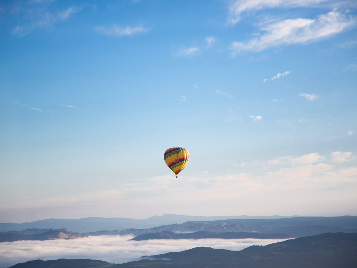 A single balloon drifting over open country on a still morning