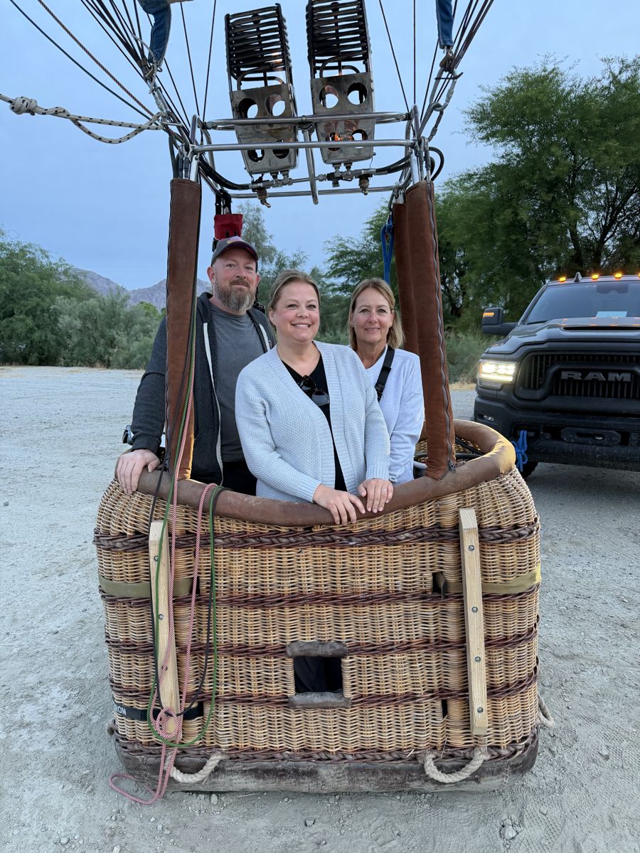 Three passengers standing in the wicker basket under the burners