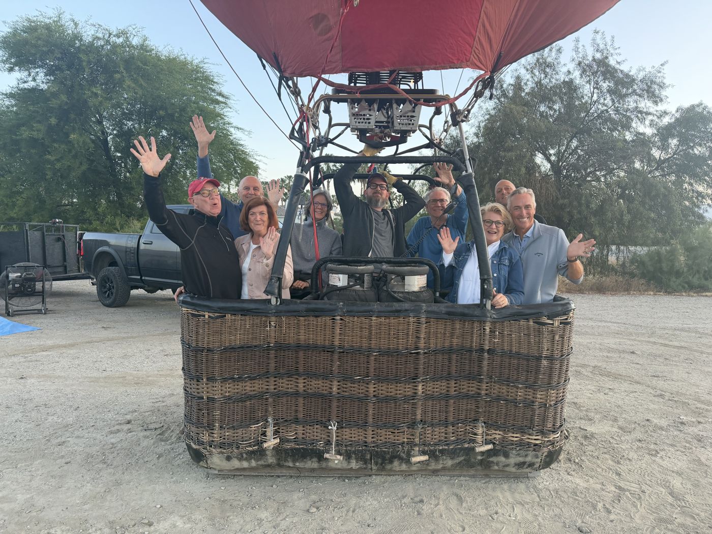 A small group of smiling passengers waving from the basket before launch
