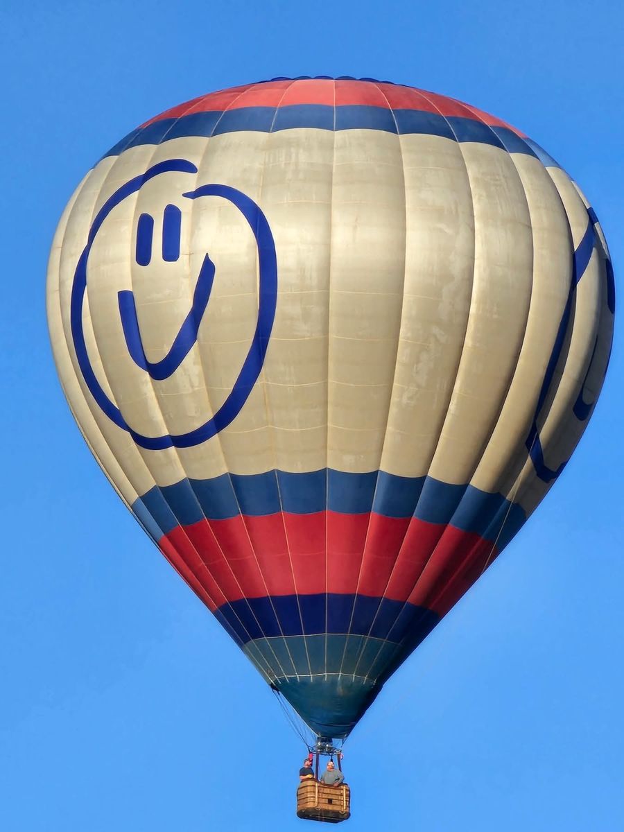 A close view of a cream balloon with a blue smiley face and red and blue bands