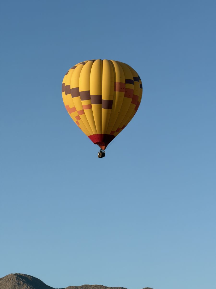 A yellow and orange balloon against clear blue sky